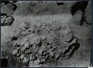 Pottery vessels and broken sherds lying in excavated soil at Idalion Acropolis, seen from above.