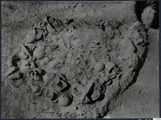 Excavated hollow at Idalion Acropolis with many broken and whole pottery vessels lying in the soil