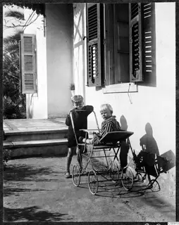 Martin and Stefan Gjerstad with a small metal pram outside a white house, Nicosia