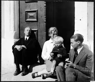 Two men, a woman and a small boy sitting on a step by a wooden door at 11 Gladstone Rd, Nicosia.