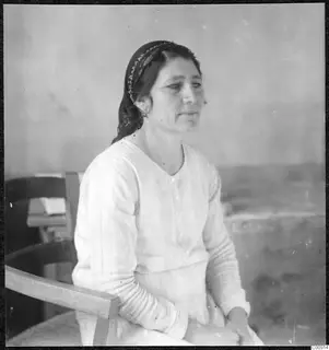 Portrait of Maria in Nicosia, a woman with a dark headscarf seated in a wooden chair.