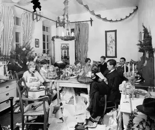 Christmas Eve 1927 gathering in a Nicosia room, with torn wrapping paper scattered over the floor and a decorated tree.