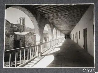 Arcaded covered gallery with a timber roof and a domed church with bell tower, at the monastery at Lambousa