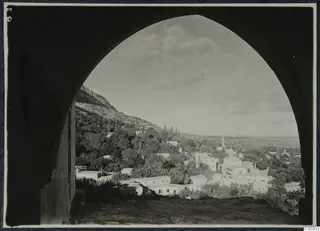 View through a pointed arch over the village of Lapithos, with houses, trees and a hillside