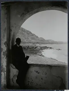 John Lindros seated in an arched vault of Lambousa monastery, with the sea and hills visible through the opening