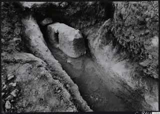 Tomb 422 at Lapithos Kastros during excavation, showing a narrow cut with a large stone block