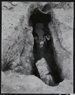 Tomb 422 at Lapithos Kastros during excavation, with flat stone slabs and pottery in the tomb chamber.