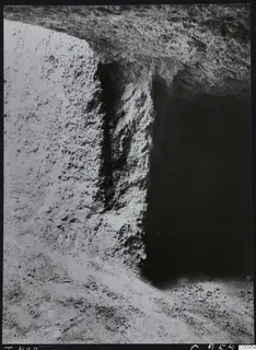 Tomb 422 at Lapithos during excavation, showing a cut rock face beside a dark tomb chamber opening