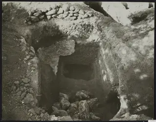Tomb 427 at Lapithos during excavation, showing the tomb chamber opening behind a sloping cut with loose stones on the floor