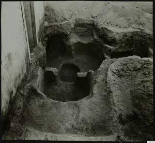Tomb 501 at Lapithos: excavated cutting with rock-cut openings and a plastered wall at the left