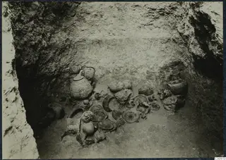 Pottery vessels and sherds lying on the floor of a cut pit at Idalion, seen from above.