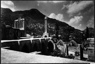 Monastery at Bellapais with pointed arches, a tower topped by a cross, and a steep hillside behind
