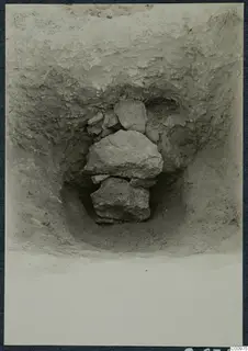 Excavation pit at Idalion with a stack of large stones lying in the soil.