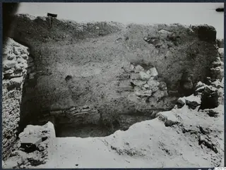 Excavated section at Idalion acropolis with a stone wall face, rubble stones and a small dark box in the lower left.