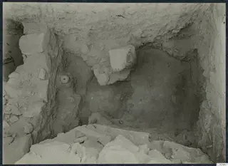 Excavation trench at Idalion Acropolis with pale stone blocks and round objects lying in the soil.