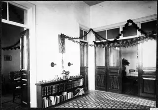 Interior of the Swedish Institute, 11 Gladstone Road, Nicosia, with a bookcase, vessels and garlands.