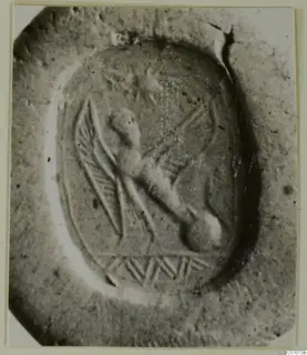 Engraved oval stone seal with a winged creature and a hatched band below it, shown close up