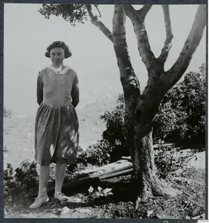 Mrs Gjerstad standing beside a tree on stony ground, hands behind her back