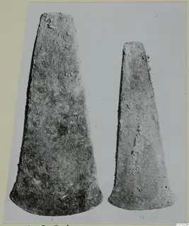 Two tapering metal axe blades photographed side by side, from Lapithos