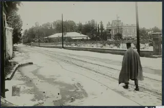 Snow-covered Gladstone Road in Nicosia, with a man in a long cape walking along it.