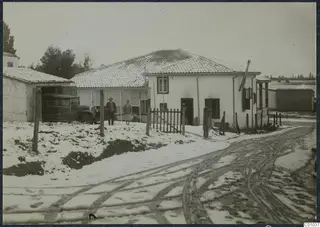 The Swedish house in snow, Nicosia, with a parked car and two people standing by the wooden gate