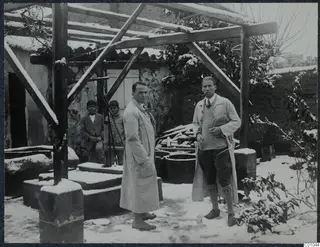 Erik Sjöqvist and Alfred Westholm in a snowy courtyard under a wooden pergola, with two boys behind them.