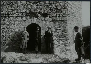 Four people standing by an arched doorway in a rough stone tower at St. Hilarion