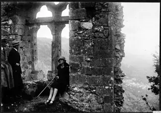 Ruined stone wall with arched openings overlooking the Kyrenia Mountains, with two men standing and a woman seated on the ledge