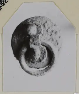 Bronze fragment coiled into a spiral loop, shown on a pale card mount