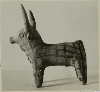 Terracotta figurine of a horned cattle with dark painted bands in a grid pattern