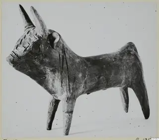 Terracotta figurine of a bull with long upturned horns and incised markings on the head and body.