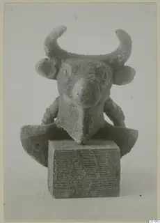 Small horned bull-head figure mounted on a block, front view