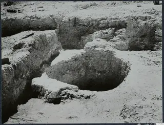 Excavated well at Idalion: a circular pit cut into layered soil, with a rough stone lip on one side