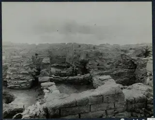 Excavated stone and mud-brick walls at Idalion Acropolis, with rubble and a small excavated room.