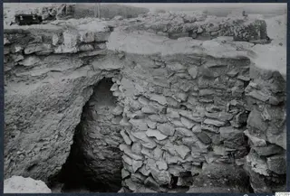 Excavated stone walls and a dark arched opening at Idalion Acropolis