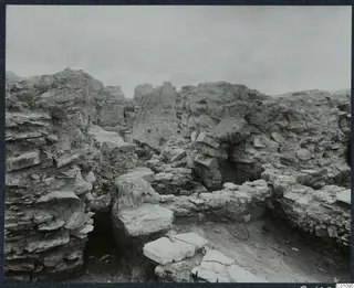 Overall view of grid square K 4 at Idalion, looking south, showing excavated walls and flat stone slabs.