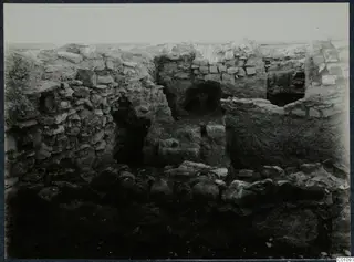Standing ruined stone walls with arched openings and fallen boulders at the Idalion acropolis during excavation