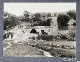 Copy photograph of the Old Mill at Kalavasos, a stone building with an arched opening and horses at its doorway.