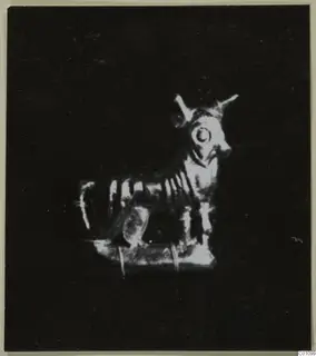 Small figurine of a horned animal standing on a flat rectangular base