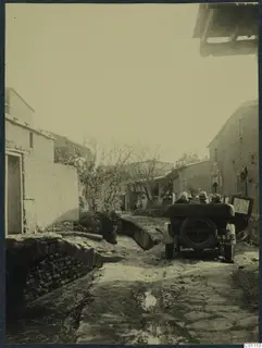 Open car on a cobbled village street at Kythrea, with a stone-edged water channel running beside the road.