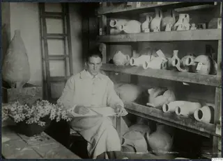 Alfred Westholm seated with a notebook beside shelves of pottery jars at the Swedish Institute, Nicosia