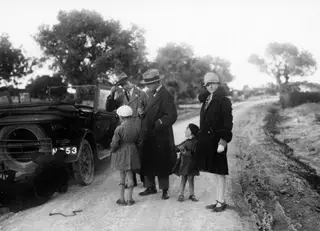 Open car on a dirt road at Idalion, with two men, a woman and two children standing beside it.