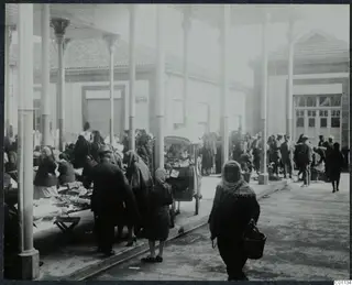 Market square in Nicosia: a crowd of people walking and trading under a colonnade of tall white pillars