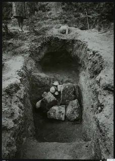 Dromos of Tomb 4 at Marion, an excavated cut with a heap of stones, with a person's legs at the top edge.