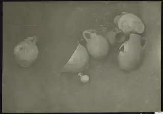 Several clay jugs and jars lying on the ground during excavation at Marion, Tomb 4.