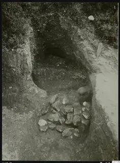Tomb 8 at Marion during excavation, with a dromos cut into the earth and a heap of stones in the foreground.