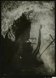 Excavation trench at Marion with a tool at the right edge and a long shadow falling across the cut wall.