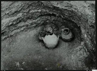 Pottery vessels in situ in Tomb 8 at Marion during excavation, seen in a hollow in the soil wall