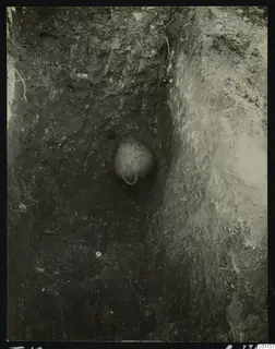 Tomb 10 at Marion during excavation, with a rounded vessel set into the soil of a narrow cut.