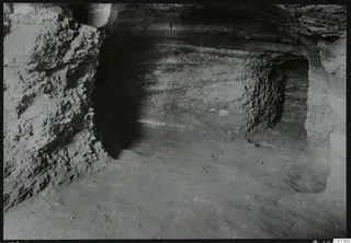 Rock-cut tomb passage at Marion during excavation, with layered rock walls and a sandy floor.
